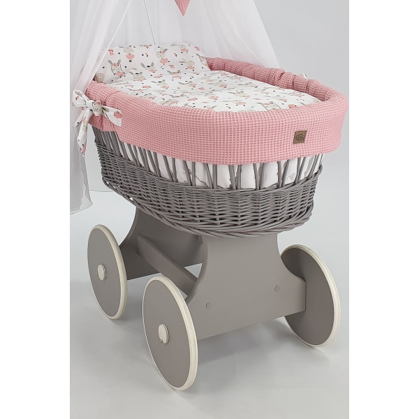 culla di vimini grigia con drappeggio rosa chiaro