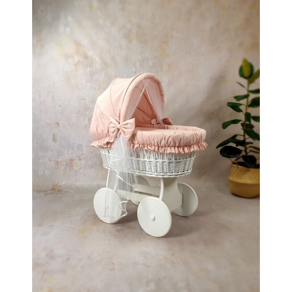 Culla vimini bianco con biancheria rosa