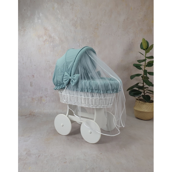 Dettaglio del lenzuolo beige e cappottina color khaki per culla in vimini
